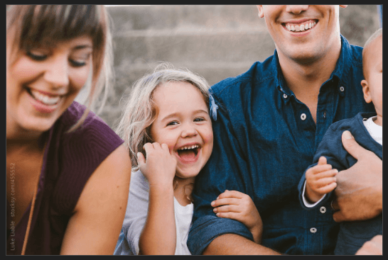 Young Girl Smiling at Camera with Family