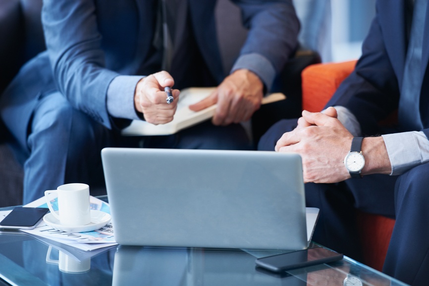 well dressed business men makes notes and discuss details displayed on a laptop